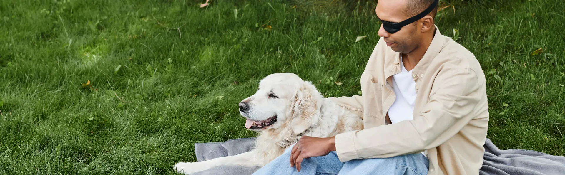 A veteran sitting on the grass with a golden retriever, symbolizing support and hope for ending veteran homelessness.